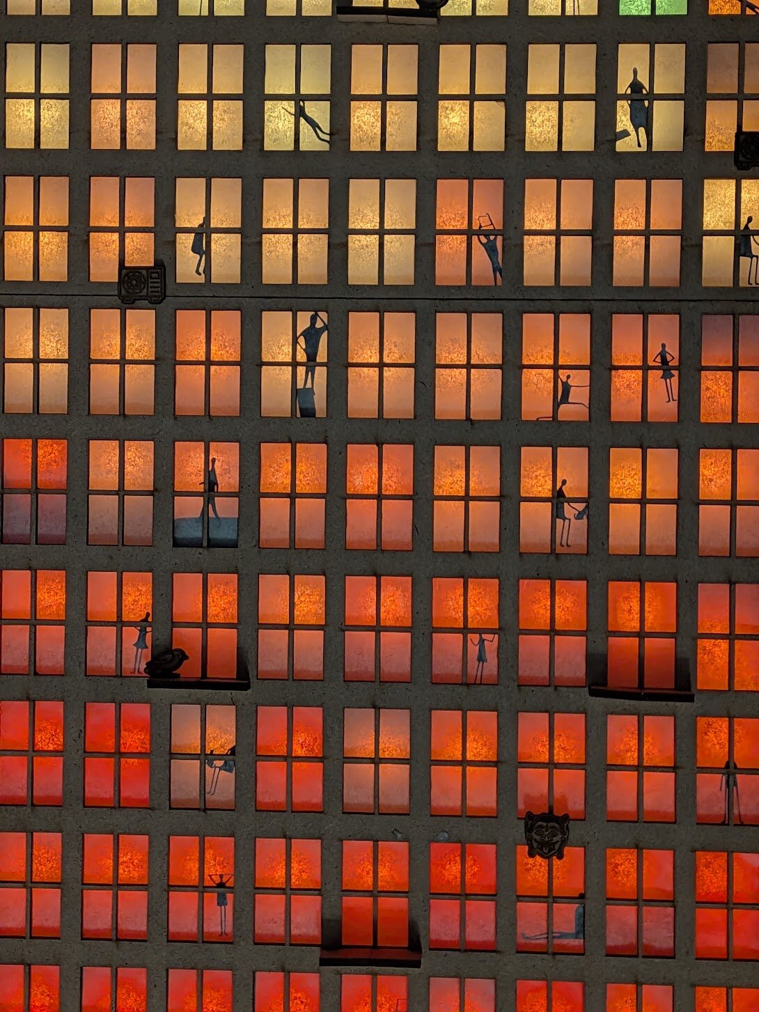 Stick-figure silhouettes glowing against the tower windows in the finished installation