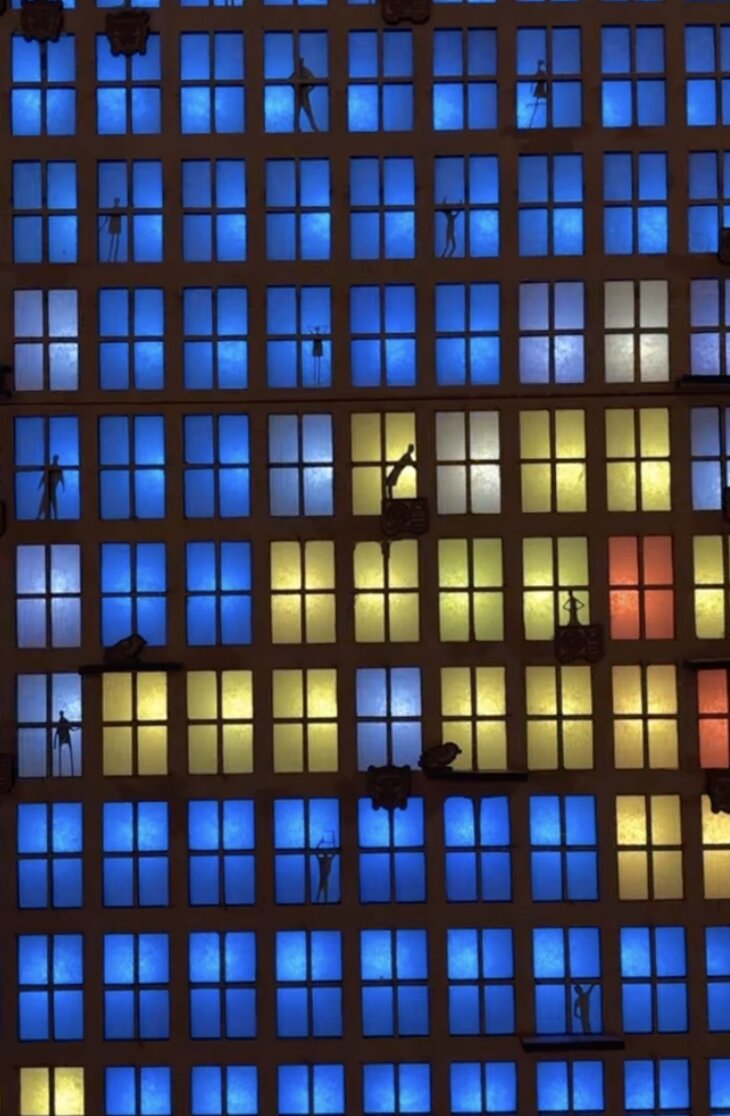 Close-up of illuminated windows on the exhibit tower with tiny stick-figure silhouettes